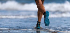 Athlete runner running on waves of sea beach