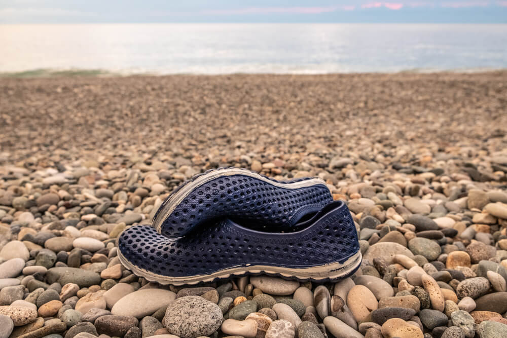 Blue rubber bathing slippers. Beach shoes on pebbles