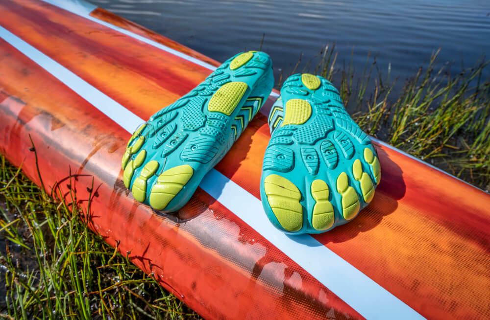 Lightweight low-profile water shoes (soles up) for kayaking and other wet sports on a deck of a stand up paddleboard